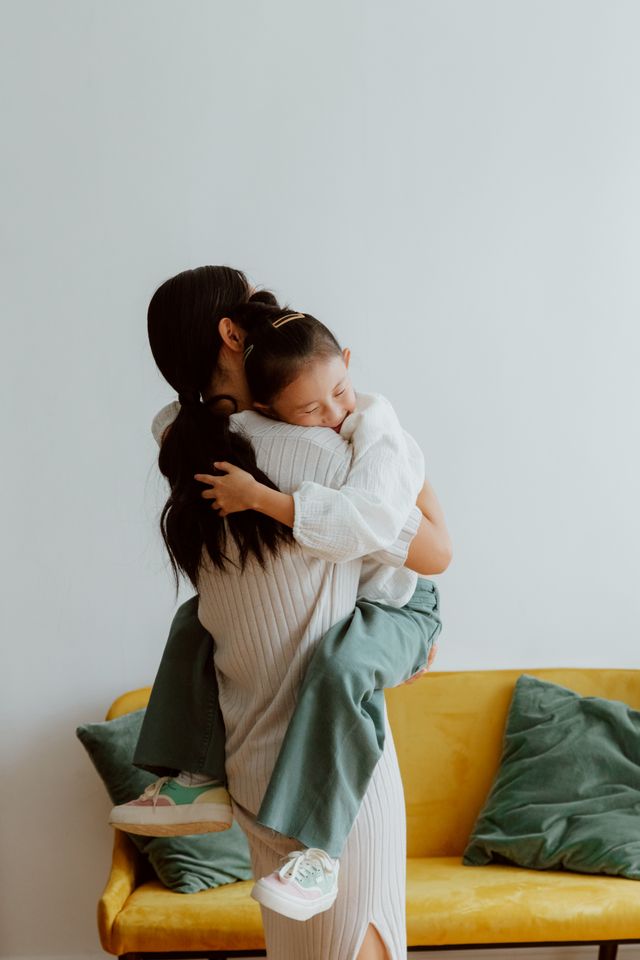 A warm embrace between mother and daughter on a cozy sofa, showcasing family love.